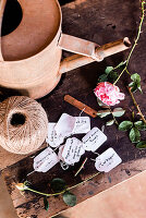 Plant labels, string, rusty watering can and a rose