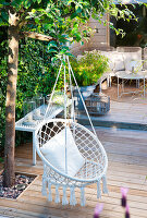 Hanging chair made of rattan with cushions on a wooden terrace in the countryside