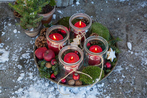 Advent wreath with lanterns, moss, and red apples in vintage bowl outside