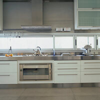 Contemporary kitchen in white and stainless steel with stone floor