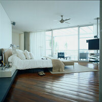 Großes, modernes, offenes Schlafzimmer mit Holzboden, Glaswänden und einem Home Entertainment Center