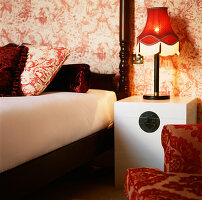 Red and white bold patterned wallpaper with red decor and a double bed in a bedroom
