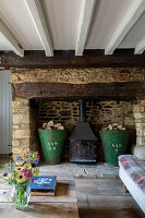 Antique metal log storage in stone fireplace with low beamed ceiling in Cirencester home Gloucestershire UK