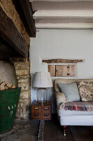 Lampe auf antikem Ablagekasten mit Metalleimer und Sofa in einem Bauernhaus in Cirencester, Gloucestershire UK