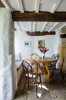 Holztisch und -stühle mit Fliesenboden in einem Bauernhaus in Cirencester, Gloucestershire, Großbritannien