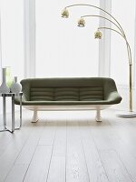 Green retro style sofa in living room with painted white floorboards