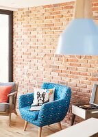 Boston Terrier cushion on bright blue geometric patterned armchair with record player beside exposed brick wall  London  UK