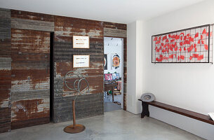Moderne Kunst und Sitzbank mit Blick durch eine Schiebetür in einem Haus in Essex, Großbritannien