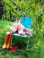 Wellington boots and blanket with folding chair under tree on riverbank
