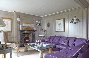 Purple sofa set in front of fireplace in living room with gray decorative paneled walls
