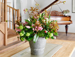 Frühlingsblumenarrangement im grauen Topf auf Holztisch