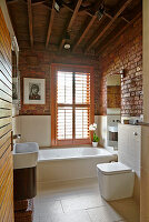 Renoviertes Badezimmer mit Backsteinwänden und Holzbalkendecke