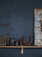 Decorative still life with vintage objects on a wooden shelf in front of a dark wall