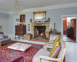 Fireplace between antique chest of drawers and console table in lounge