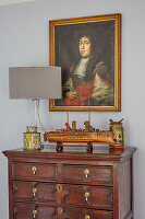 Antique chest of drawers with works of art, above a portrait painting