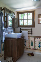 Washbasin on washstand below ornately carved mirror in bathroom with painted panels