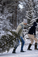 Personen und Weihnachtsbaum im winterlichen Wald