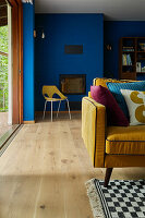 Living room with blue walls, yellow sofa and patterned carpet