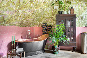 Bathroom with copper-colored freestanding bathtub and tropical wallpaper pattern