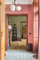 Hallway with pink tones, patterned wallpaper and tiled floor