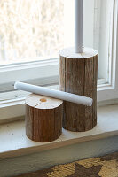 Candle holder made from wooden logs on a windowsill with a view outside