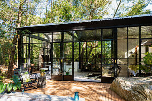 Glasshouse with wooden terrace in the forest