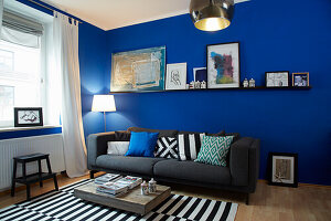 Upholstered sofa and black and white striped carpet in the living room with blue walls