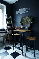 Bar table with stools in kitchen with black walls and fish motif
