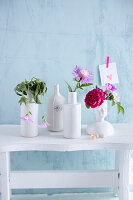 White vases with fresh blossoms, one with withered blossoms (discomfort, sickness)