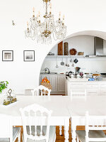 White dining table with chairs in classically designed dining area with chandelier