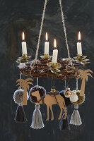 Hanging DIY Advent wreath with four lit candles and a camel with palm trees