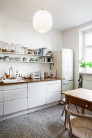 White kitchenette with wooden worktop, shelves and fridge