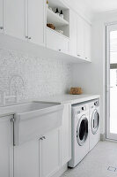 Waschküche mit weißen Einbauten und Mosaikwandfliesen