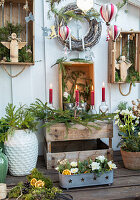 Wooden crates decorated for Christmas with candles and fir branches in front of a white wooden wall