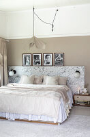 Doppelbett mit Betthaupt in Marmoroptik, darüber schwarz-weiße Fotografie