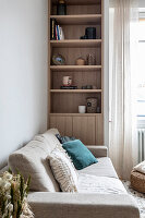 Light upholstered sofa with cushions and floor-to-ceiling built-in shelf in the living room