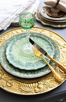 Place setting with ornate tableware and green tinted wine glass