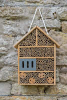An insect hotel against a natural stone wall