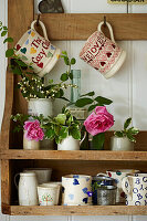 Wall shelf with cups and pink roses