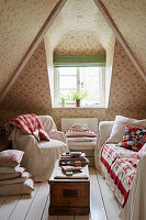 Sofa and armchair with quilt in wallpapered attic room