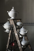 White soup tureens on an easel ladder