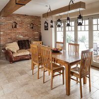 Dining area with wooden furniture and leather couch in front of a rustic brick wall