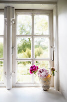 Peonies in a decorative vase on a windowsill