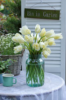 White tulips (Tulipa) in a vase and saxifrage (Saxifraga) in a basket