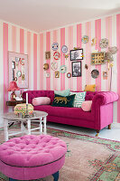 Pink sofa, above photos and wall plates in lounge with pink striped wallpaper