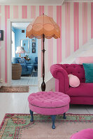 Pink sofa, next to it floor lamp in lounge with pink striped wallpaper