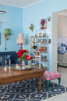 Anitker Couchtisch mit Blumen und weißes Regal im Wohnzimmer mit hellblauen Wänden