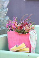 Gartenblumen in pinkfarbene Tasche auf Metallbank
