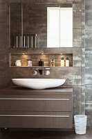 A countertop washbasin with illuminated wall niche and a mirrored cabinet above it