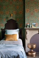 Single bed with wooden bed head in the bedroom with patterned wallpaper